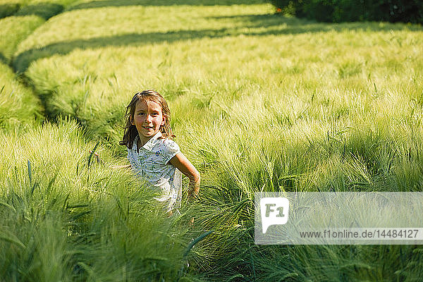 Porträt lächelndes Mädchen in ländlichem  grünem Weizenfeld