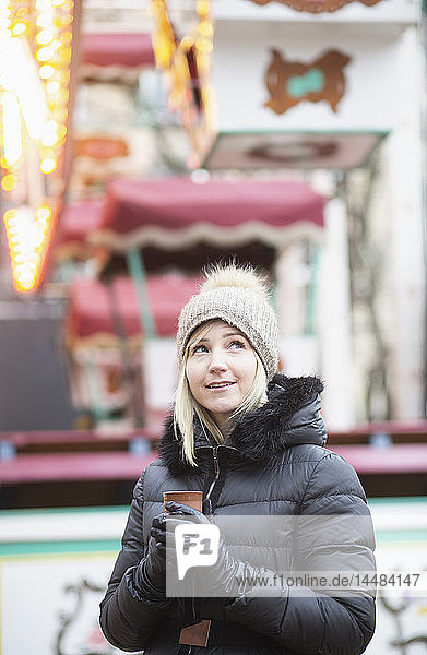 Frau in warmer Kleidung trinkt Tee beim Karneval