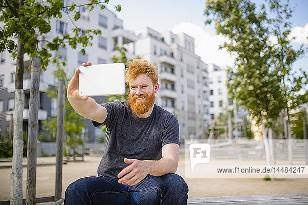 Lächelnder Mann mit Bart macht Selfie mit digitalem Tablet in der Stadt