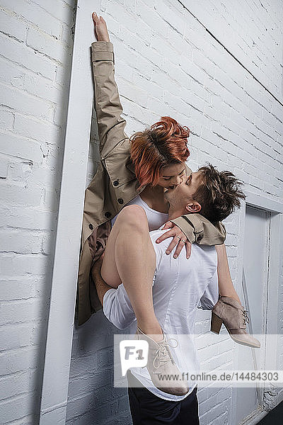 Moderne Tänzer küssen sich vor einer weißen Backsteinmauer