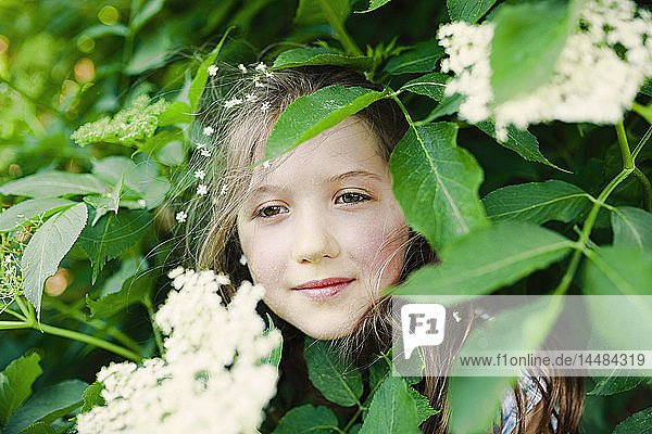 Porträt heiteres Mädchen in blühendem Busch stehend
