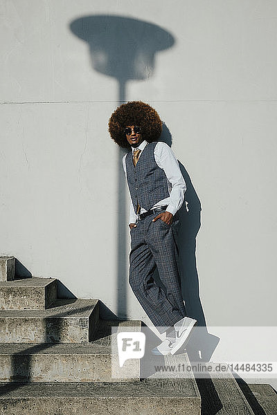 Porträt selbstbewusster  cooler  gut gekleideter junger Mann mit Afro auf städtischen Stufen