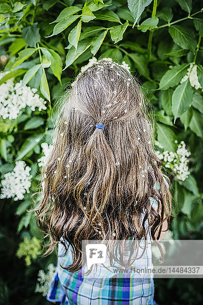 Mädchen mit Blumen im Haar am blühenden Busch
