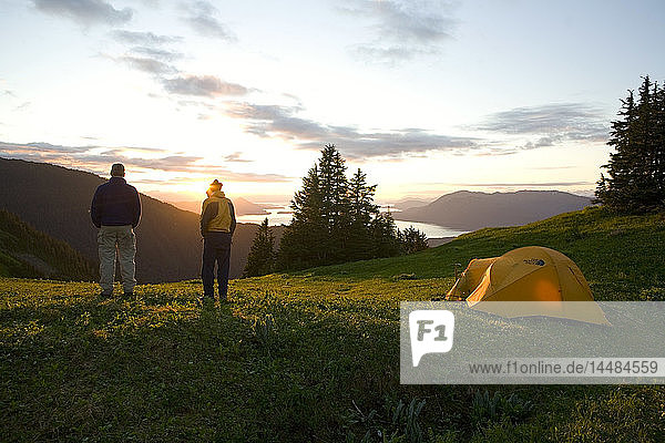 Zwei Bergsteiger stehen im Abendlicht vor ihrem Zelt im Hochgebirgslager am Eagle Peak auf Admiralty Island im Südosten Alaskas Sommer