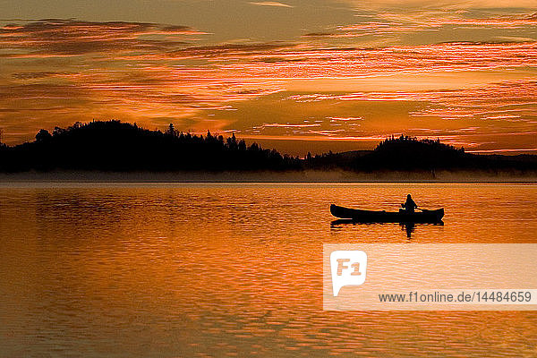 Silhouette einer Person beim Kanufahren auf einem See bei Sonnenuntergang Boundary Waters Sommer