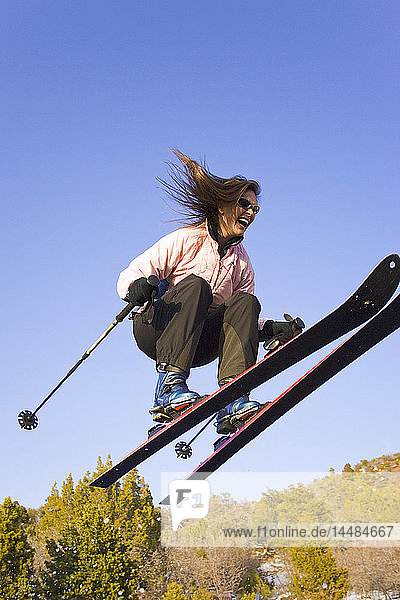 Junge Frau springt in der Luft beim Skifahren auf der Piste Dixie National Forest Utah Winter