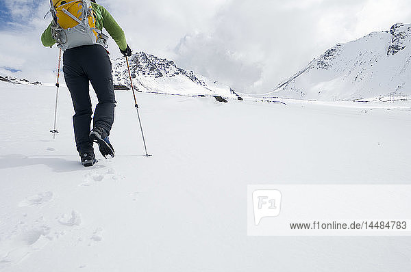 Person beim Wandern im Schnee mit Skistöcken in den Chugach Mountains  Southcentral  Alaska
