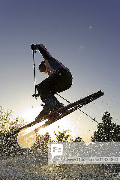 Junge Frau in der Luft springt auf Skiern bergab Dixie National Forest Utah Winter Backlit von Sonne