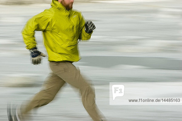 Mann läuft entlang des Turnigan Arm auf bröckeligem Eis und Schlamm im Winter Girdwood Alaska Southcentral