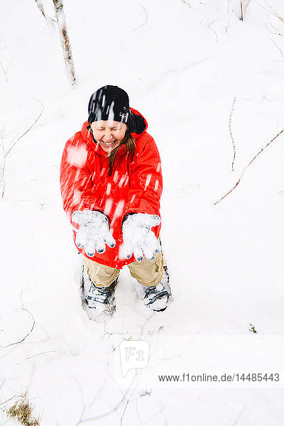 Frau blinzelt  als Schnee auf sie fällt  während sie mit Schneeschuhen auf dem Volunteer Trail unterwegs ist  Wrangell Island  Südost-Alaska  Winter