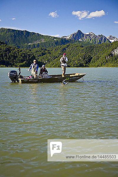 Ein Spinnfischer fängt einen Silberlachs  während er in einem Boot in den Big River Lakes in der Redoubt Bay State Critical Habitat Area in Süd-Zentral-Alaska steht  im Sommer