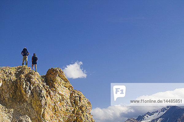 Wanderer steht auf einem Felsvorsprung mit Blick auf das Tal des Toklat River Polychrome Pass Denali Nat Park Alaska
