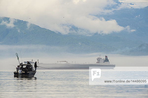 Eine Gruppe von Fischern in einem Boot auf dem Prince William Sound in der Nähe von Valdez mit einem Öltanker im Hintergrund  Süd-Zentral-Alaska