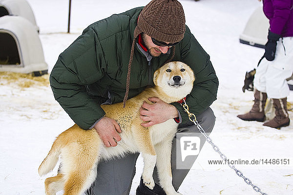 Tourist umarmt einen Schlittenhund  Alyeska Resort in der Nähe von Moose Meadows bei Girdwood in Süd-Zentral-Alaska