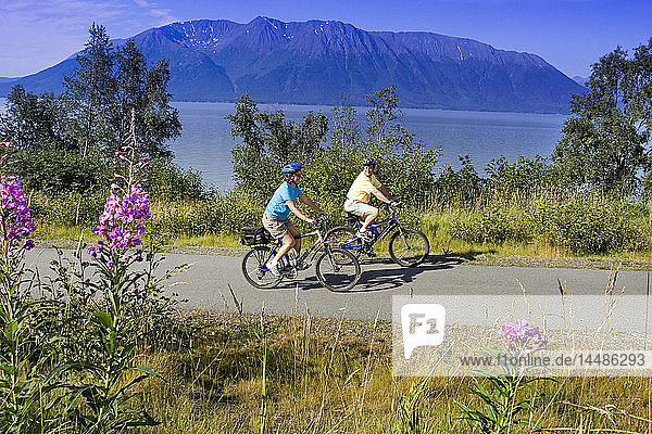 Couple riding bikes together on Coastal Trail near Indian Alaska Turnagain Arm  SC Summer.