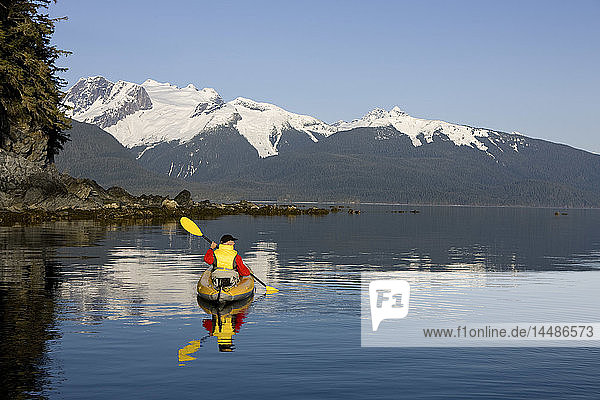 Kayaker paddles the shoreline on a calm afternoon in Lynn Canal just outside Berners Bay in Alaska´s Tongass Forest  Inside Passage.