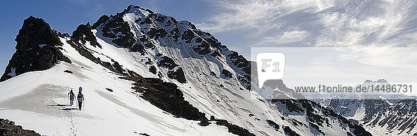 Ein Backcountry-Snowboarder und ein Skifahrer wandern auf dem Westkamm des Powerline Pass in der Nähe von Anchorage  Alaska