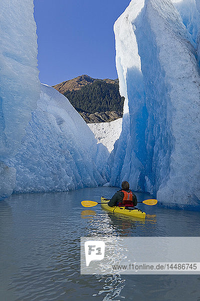 A kayaker paddles and explores the seracs of Mendenhall Glacier on a crisp Fall morning with Mt. McGinnis in the background  Southeast Alaska