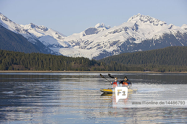 Kayakers paddle the calm waters of Alaska´s Inside Passage with Herbert Glacier in the background  Tongass National Forest near Eagle Beach State Recreation Area.