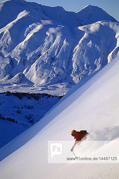 Extremskifahrer fährt auf Skiern einen steilen  schneebedeckten Berg hinunter Chugach Mountains Southcentral Alaska Winter
