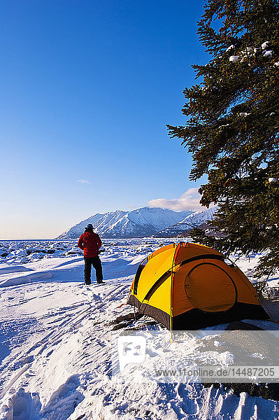 Ein Mann auf seinem Winterlagerplatz am Bird Point mit dem Turnagain Arm im Hintergrund  Southcentral Alaska