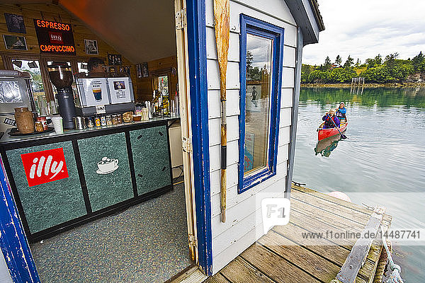 Zwei Frauen in einem Tandem-Kanu paddeln zu einem schwimmenden Kaffee- und Hotdog-Stand in Halibut Cove  Alaska