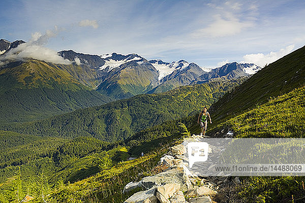 Young adult Hispanic woman hiking to the top of the tram on Mt. Alyeska above Girdwood in Southcentral Alaska