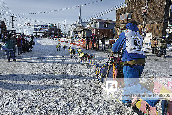 Wade Marrs runs into the finish chute on the way to the Nome burl arch finish line during Iditarod 2015