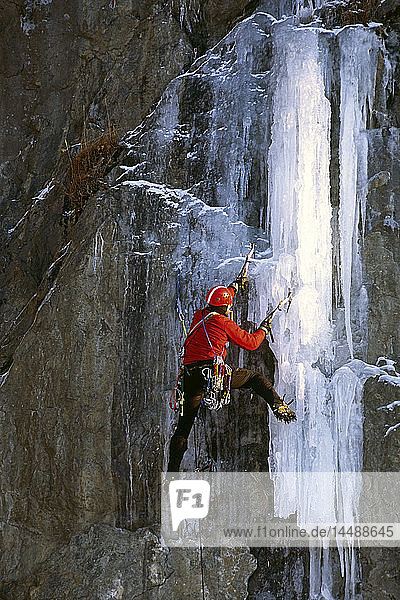 Männlicher Eiskletterer benutzt Eispickel  um einen gefrorenen Wasserfall am Turnagain Arm Chugach Mtns SC Alaska zu erklimmen