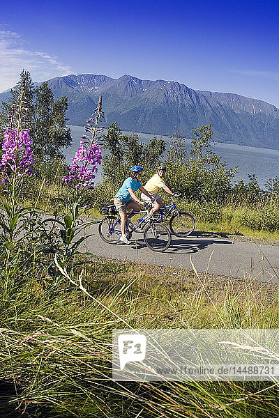 Couple riding bikes together on Coastal Trail near Indian Alaska Turnagain Arm  SC Summer.