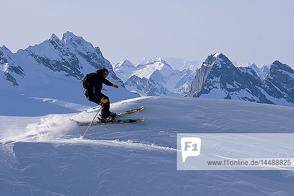 Alpine skier skiing on the Juneau Ice Field and Rhino Peak in the background in Southeast Alaska. Composite
