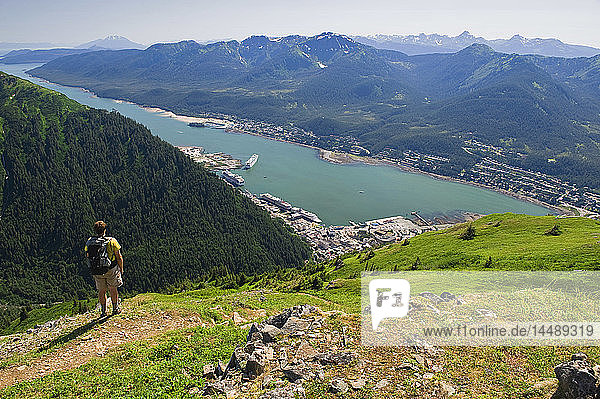 A hiker takes in the view of Gastineau Channel  Douglas Island  and Downtown Juneau from the top of Mt. Juneau in Southeast Alaska during Summer