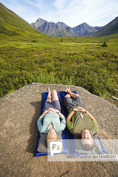Männlicher und weiblicher Wanderer entspannen sich auf einer Isomatte und hören Musik auf dem iPod entlang des South Fork Eagle River Trail Chugach State Park Alaska Sommer