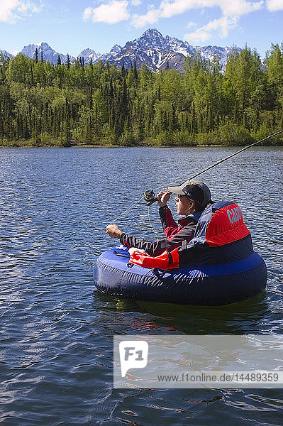 Fliegenfischerin im Schwimmrohr wirft im Sommer Regenbogenforellen am Weiner Lake in Süd-Zentral-Alaska aus