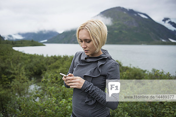 Frau  die in Portage Valley  Southcentral Alaska  mit ihrem Smartphone eine SMS schreibt