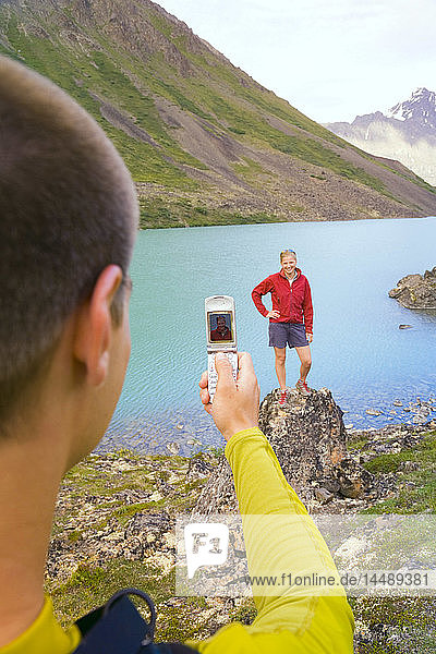 Wanderer fotografiert mit seinem Handy einen Freund am Eagle Lake im Chugach State Park Alaska Sommer