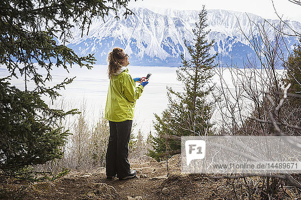 Wanderin auf dem Bird Ridge entlang des Turnagain Arm und mit einem Mobiltelefon  Southcentral Alaska  Frühling