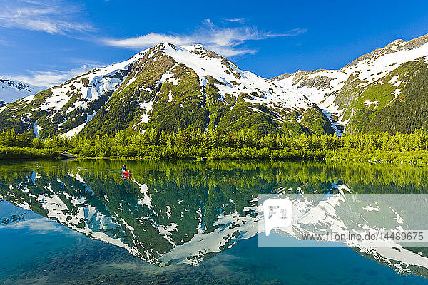 Person canoeing in small lake in Portage Valley of Chugach National Forest during Spring in Southcentral Alaska