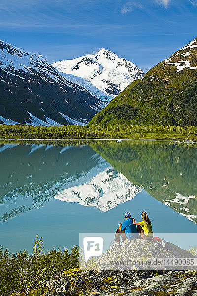 Zwei Wanderer entspannen sich am Portage Lake und genießen den Blick auf den Byron Peak  Portage Valley  Southcentral Alaska im Sommer