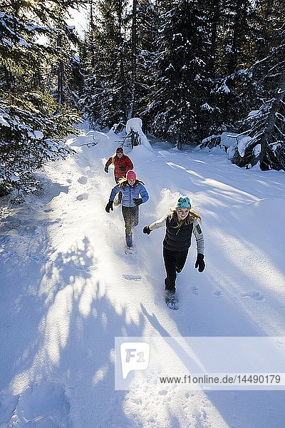 Three young women on snowshoes enjoy the outdoors near Homer  Alaska during winter.