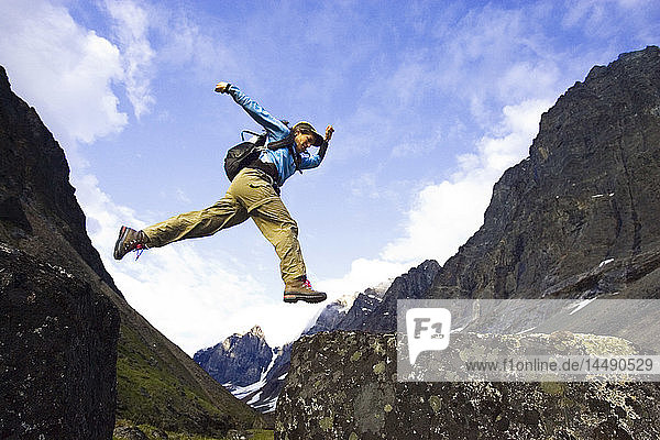 Woman rock hopping while hiking Lake Clark National Park near Turquoise Lake Southcentral Alaska Summer