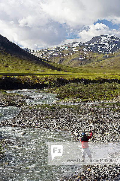 Blick auf einen Mann beim Fliegenfischen auf dem Chandalar River entlang des Dalton Highway im Sommer in Alaska