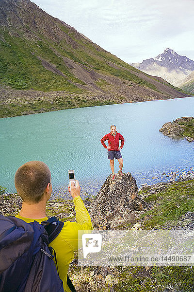 Wanderer fotografiert mit seinem Handy einen Freund am Eagle Lake im Chugach State Park Alaska Sommer