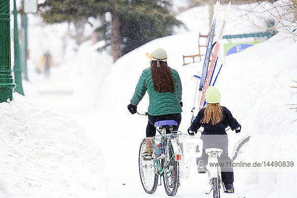 Mutter und Tochter fahren im Winter mit dem Fahrrad auf den Straßen von Crested Butte  Colorado