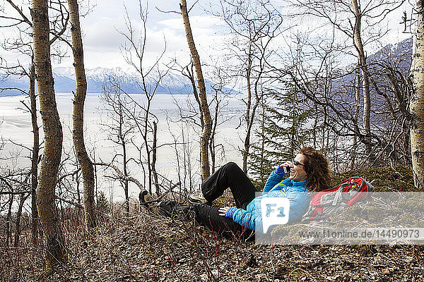 Wanderin  die sich auf dem Bird Ridge am Turnagain Arm ausruht und ein Mobiltelefon benutzt  Southcentral Alaska