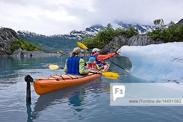 Family kayaking in Shoup Bay close to an iceberg from Shoup Glacier  Prince William Sound  Southcentral Alaska
