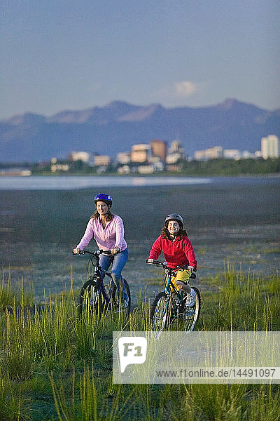 Family riding bicycles on beach next to Tony Knowles Coastal Trail Anchorage Alaska Summer