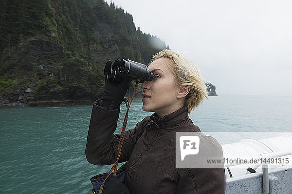 Frau mit Fernglas zur Beobachtung von Wildtieren auf einer Kreuzfahrt durch die Resurrection Bay  Seward  Süd-Zentral-Alaska