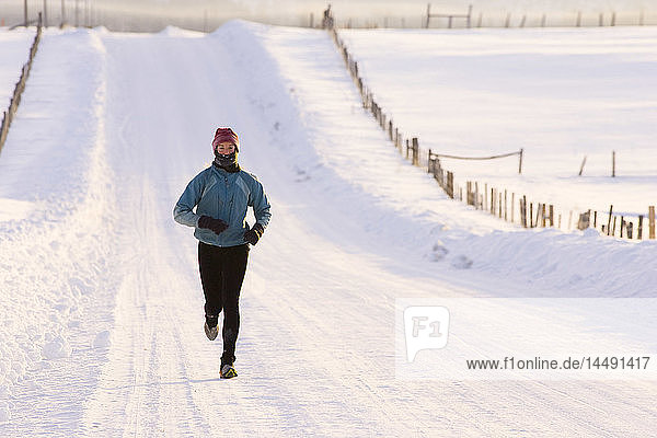 Frau joggt im Winter auf einer Landstraße in der Nähe von McCall  Idaho USA