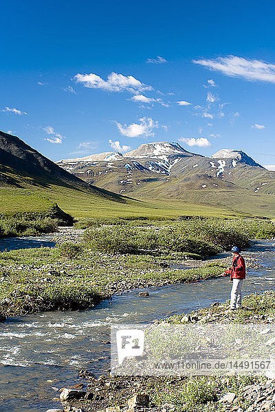 Scenic view of man fly fishing on the Chandalar River along the Dalton Highway during Summer in Alaska